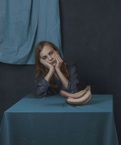 Portrait of a person sitting near the table  with white banana