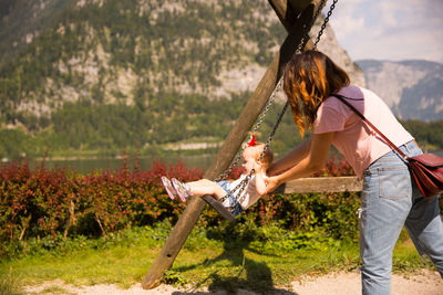 Side view of mother swinging girl in playground