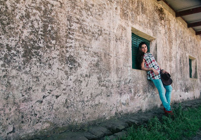 Portrait of woman standing by window of built structure