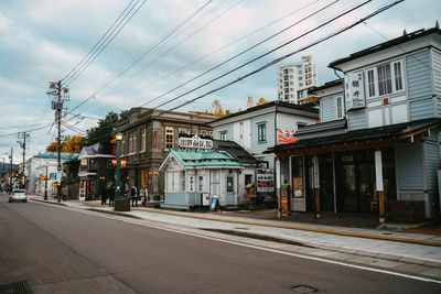 Road by buildings in city against sky