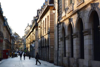 People walking at rue de la liberte against sky