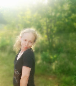 Portrait of beautiful young woman standing against trees