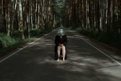 Man cycling on road amidst trees in forest