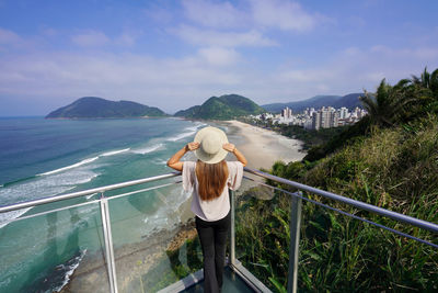 Rear view of woman standing against sea against sky