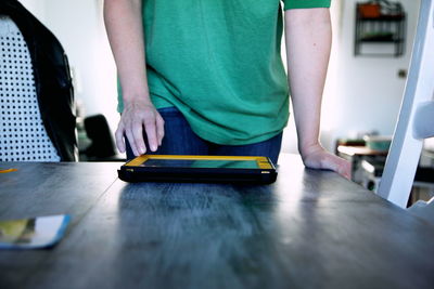 Midsection of man using digital tablet on table