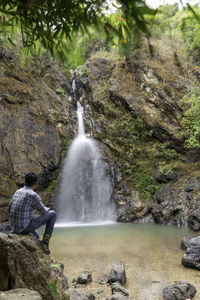 Rear view of man looking at waterfall