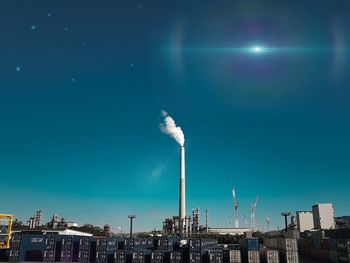 Smoke emitting from factory against blue sky