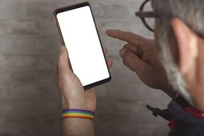 Close-up of male hands with lgbt bracelet using smartphone. hipster using a smartphone