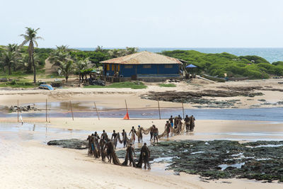 Many fishermen carrying a large fishing net to the colony after an intense day of fishing.