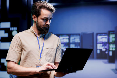 Young man using laptop while standing in office