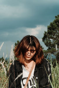 Portrait of young woman standing against sky