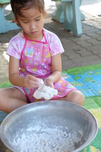 Cute girl preparing food while sitting on footpath