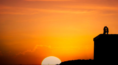 Silhouette of man against orange sky