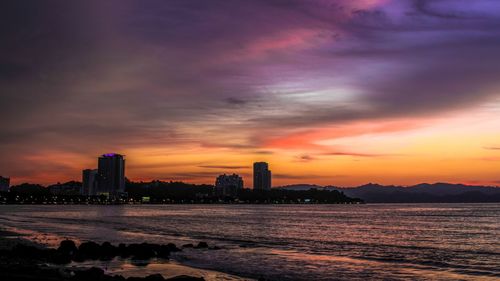 Illuminated cityscape against sky at sunset