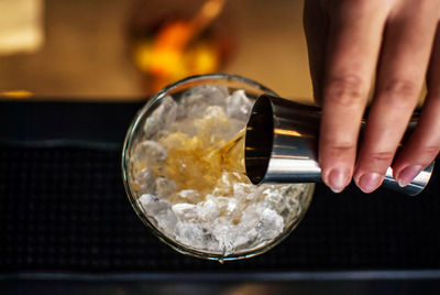 Cropped hand of woman pouring alcohol in glass on table at restaurant