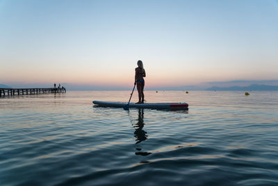 Rear view of man standing in sea against sky