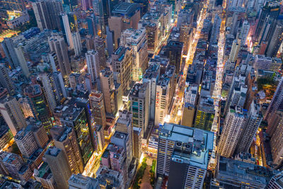 Aerial view of illuminated street amidst buildings in city at night