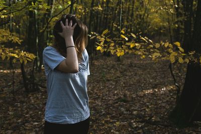 Young woman with hand in hair standing at forest