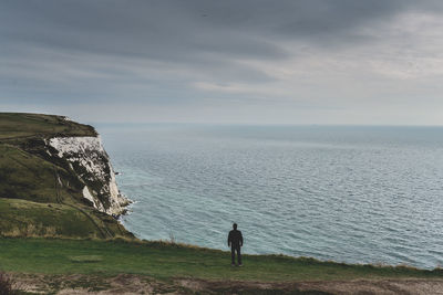 Rear view of man looking at sea against sky