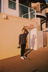 Portrait of smiling young woman standing against wall