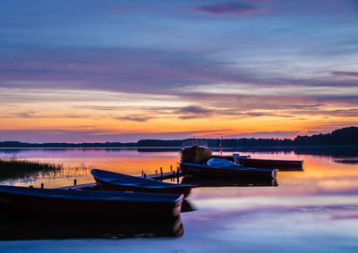 Boat moored on sea against sky during sunset