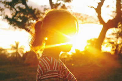 Portrait of woman standing on field against bright sun