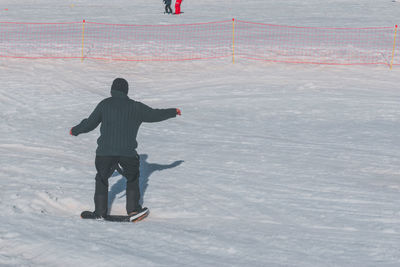 An unrecognizable caucasian man sliding down a slope on a snow skate at a ski resort in france