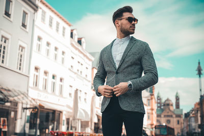 Young man looking away while standing in city