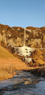 Scenic view of waterfall against clear blue sky