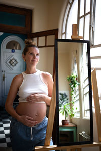 Portrait of young woman standing by window