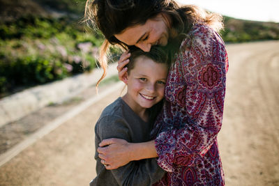 Mom and son hugging while son smiles in southern california
