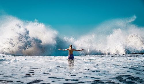 Rear view of man walking front of a waves