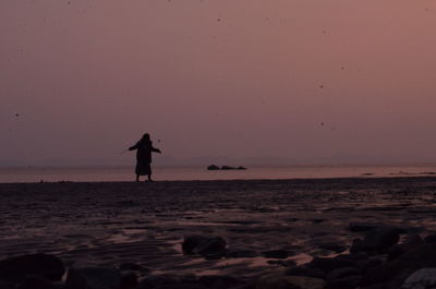 Silhouette of man on beach against sky during sunset