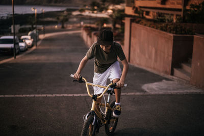 Rear view of man riding bicycle on road