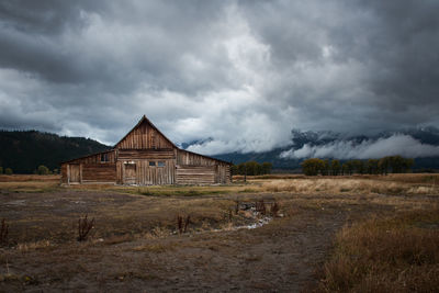 Abandoned building on field against cloudy sky