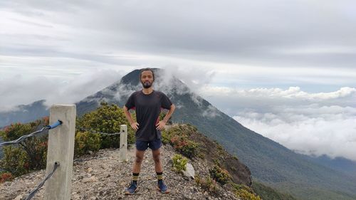 Rear view of man standing on mountain against sky