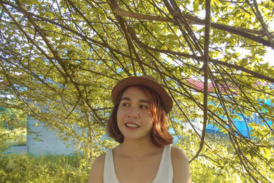 Portrait of a smiling young woman standing against trees