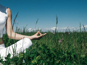 Low section of woman exercising on field against clear sky