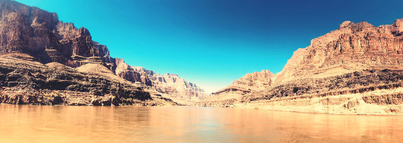 Scenic view of lake and mountains against clear blue sky