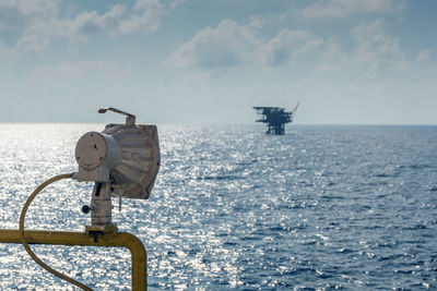 Search light on board a construction work barge with background of an offshore production platform