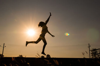 Woman man jumping against sky during sunset