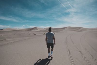 Rear view of man walking on desert