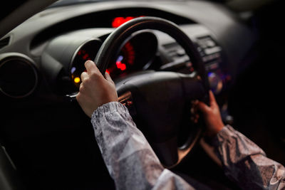 Cropped unrecognizable female driver driving modern automobile in city at night