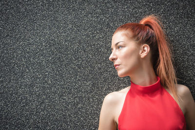 Portrait of woman standing against red wall