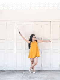 Full length of woman standing against wall