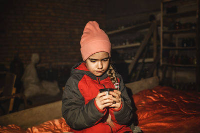 Ukrainian girl sits in bomb shelter, drinks tea and waits for end of airstrike of russian invaders