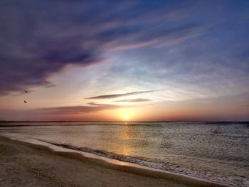 Scenic view of sea against dramatic sky during sunset