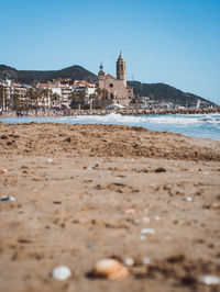 Low angle view of beach with sitges cathedral in background