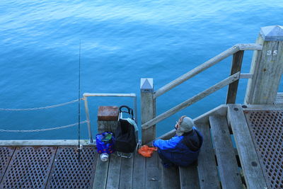 High angle view of men sitting on railing against sea