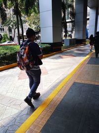 Rear view of boy walking on sidewalk